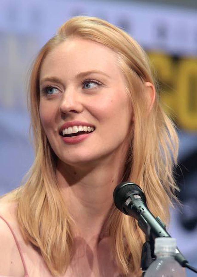 Close-up of blond woman at microphone, looking off to the side, smiling