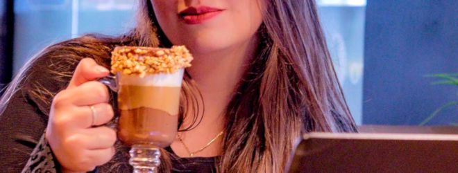 woman holds clear cup of fancy coffee